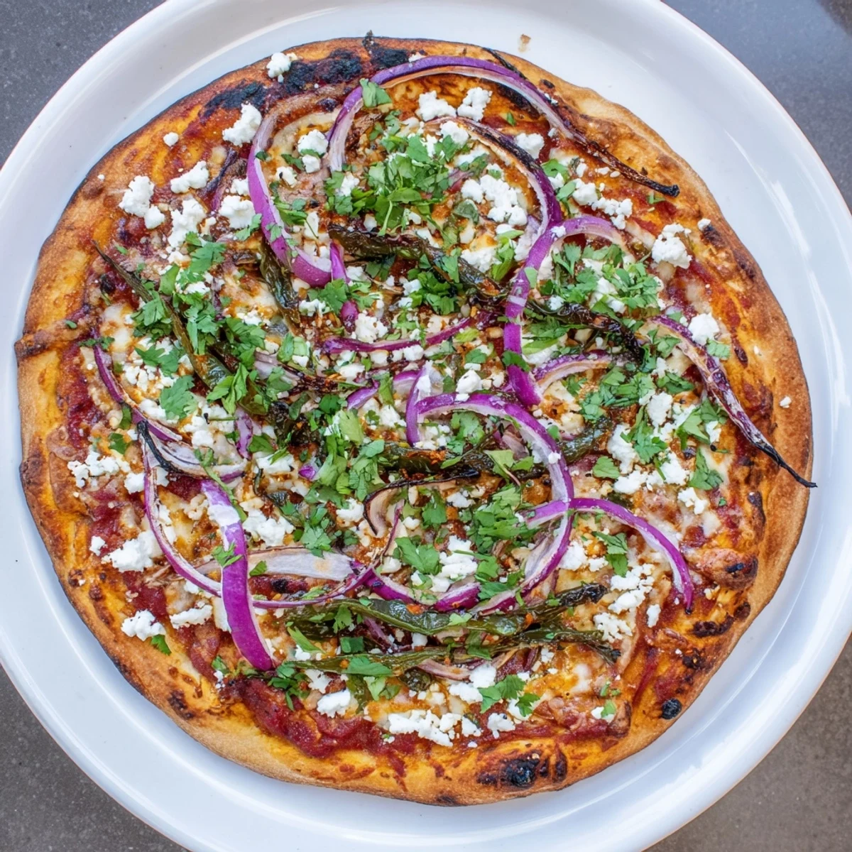 Vegetarian pizza with spicy roasted peppers bubbling alongside queso fresco and red onion