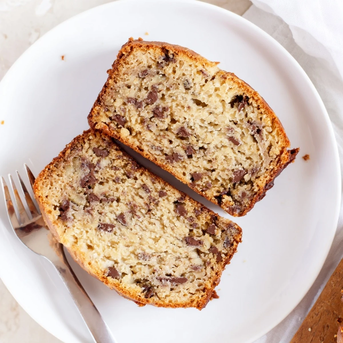 Golden brown moist banana bread with sour cream, freshly sliced on a wooden cutting board