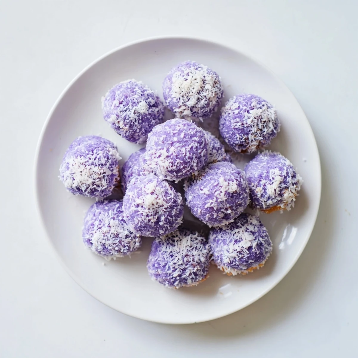 Golden Coconut Ube Besito cookies arranged on a wooden board with purple dough visible through flaky coconut coating