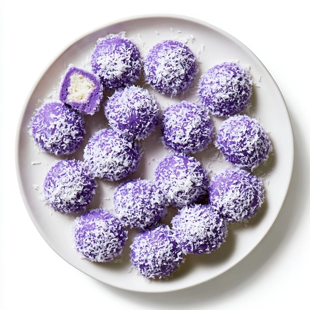 Soft purple Coconut Ube Besito cookies stacked on a white plate, lightly toasted on edges with shredded coconut topping