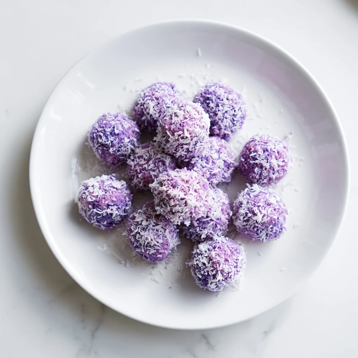Close-up of tender Coconut Ube Besito bites rolled in coconut, showing vibrant ube color and crumb texture