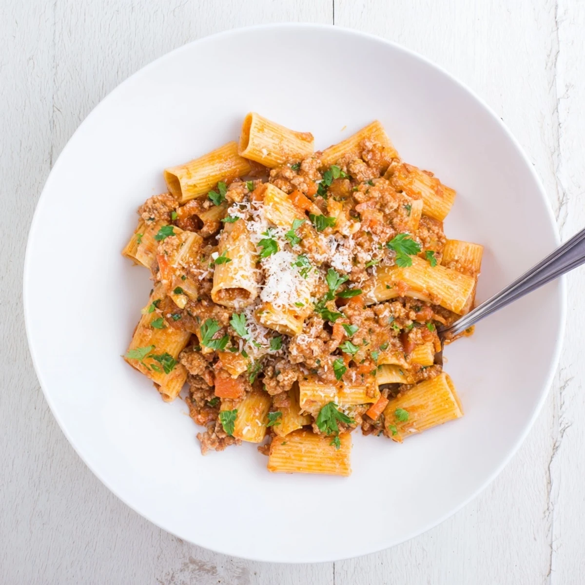 Lean ground turkey Bolognese with colorful diced vegetables and aromatic herbs served over spaghetti with grated Parmesan