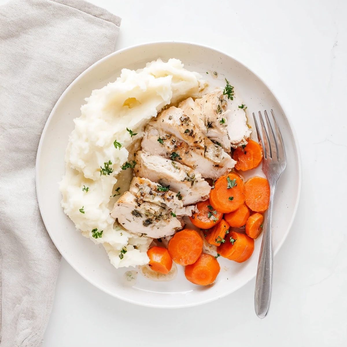 Golden herb-crusted chicken breast plated beside fluffy mashed potatoes and honey-glazed orange carrot rounds