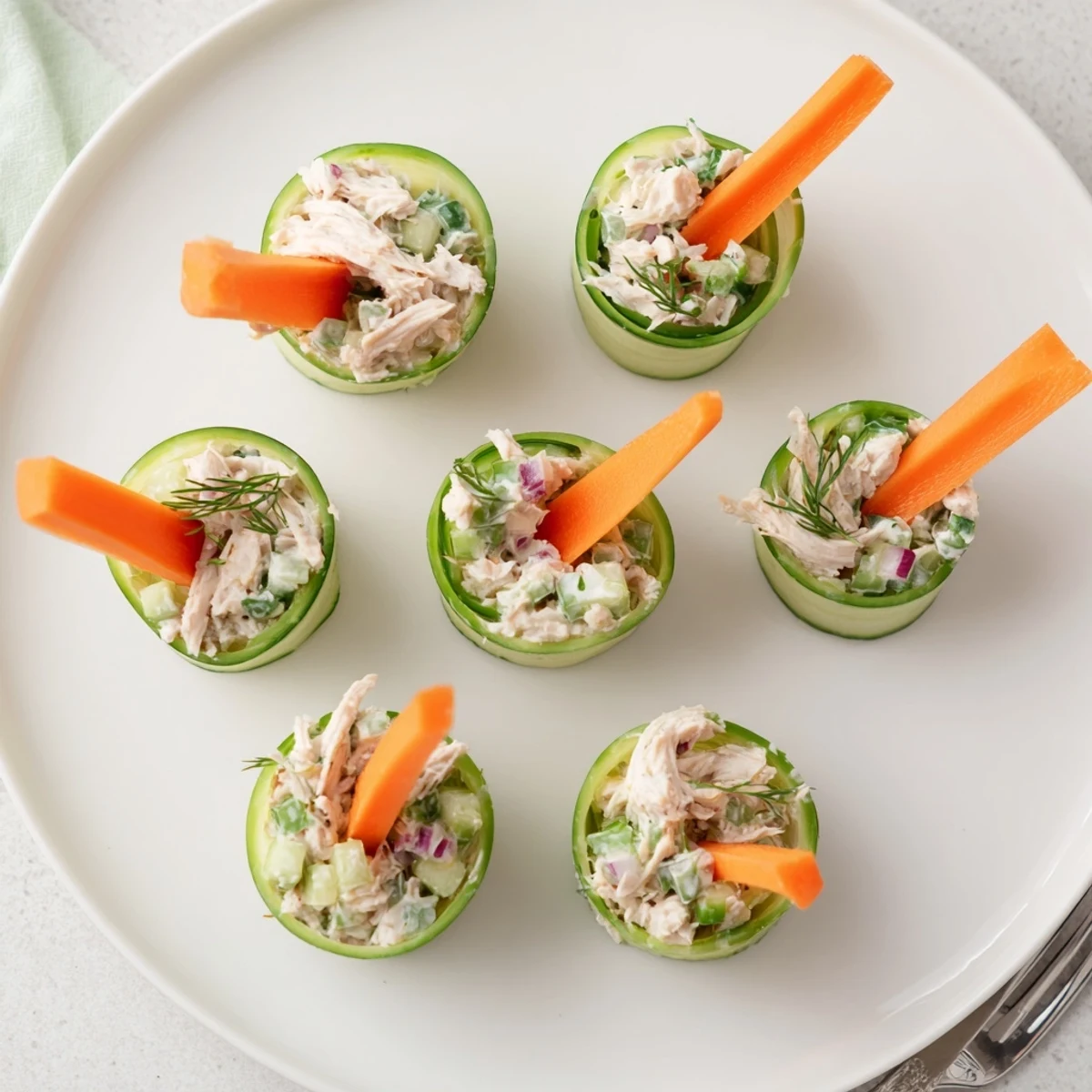 Golden chicken salad nestled inside thin cucumber ribbons offers a gluten-free bite-sized party appetizer