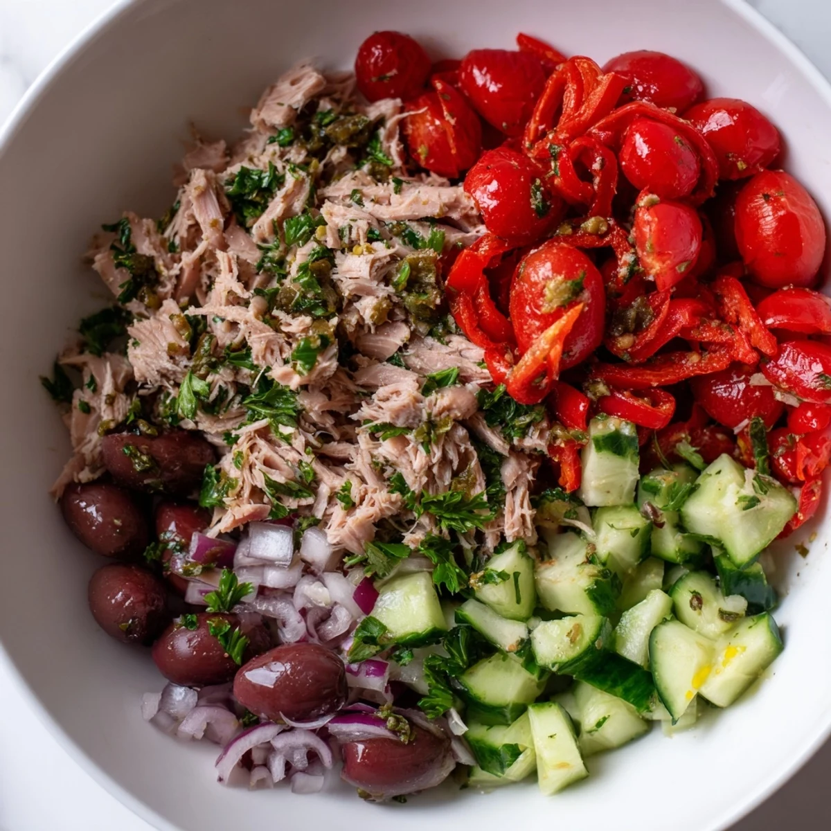 A colorful Mediterranean tuna salad with tomatoes, olives, and a bright lemon dressing.