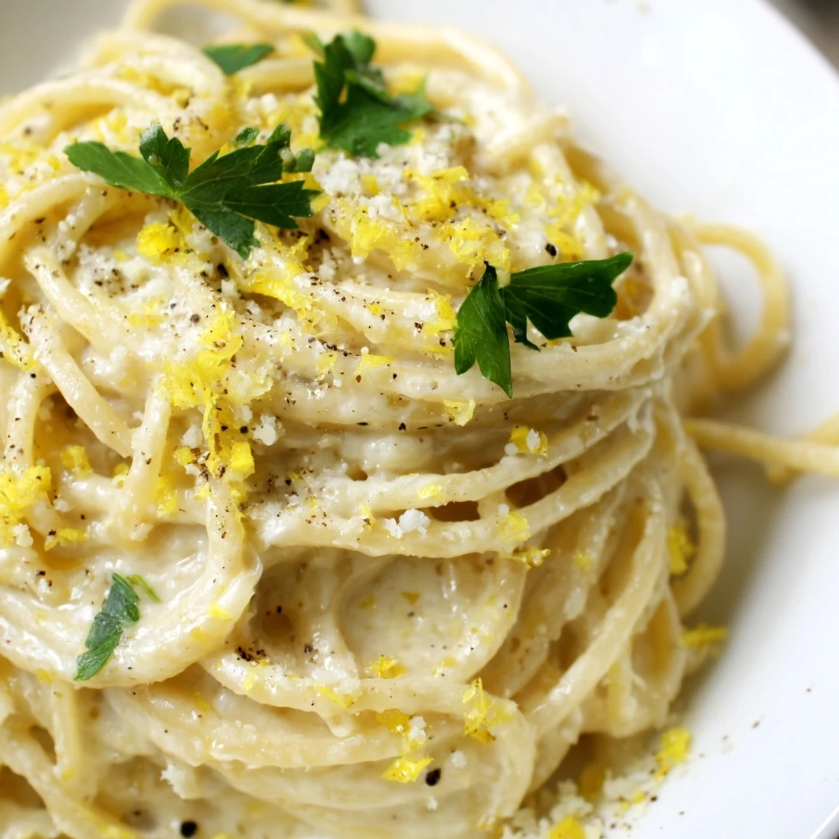 Golden spaghetti coated in zesty Parmesan lemon sauce with black pepper garnish