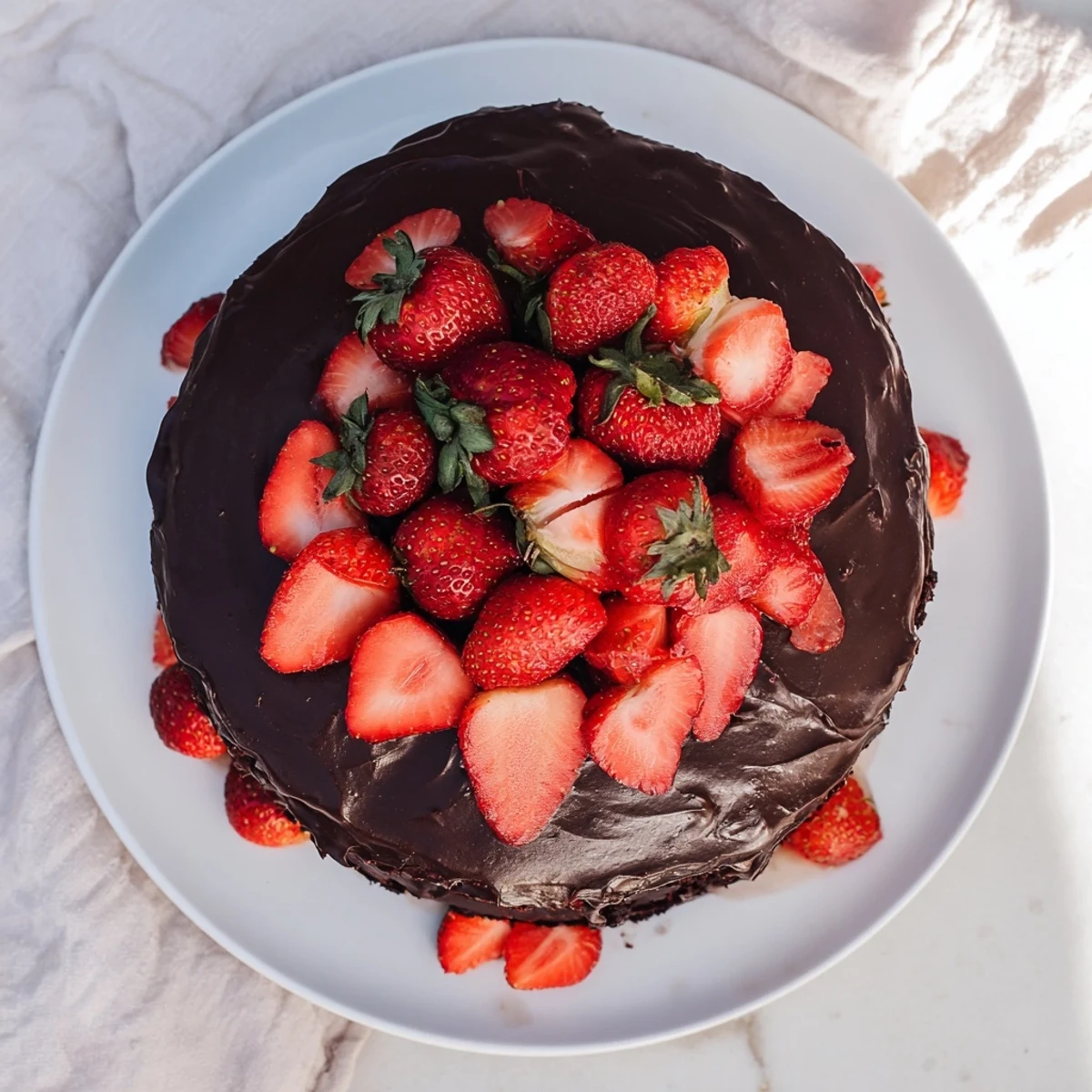 Decadent strawberry chocolate cake featuring rich ganache layers topped with fresh red strawberries