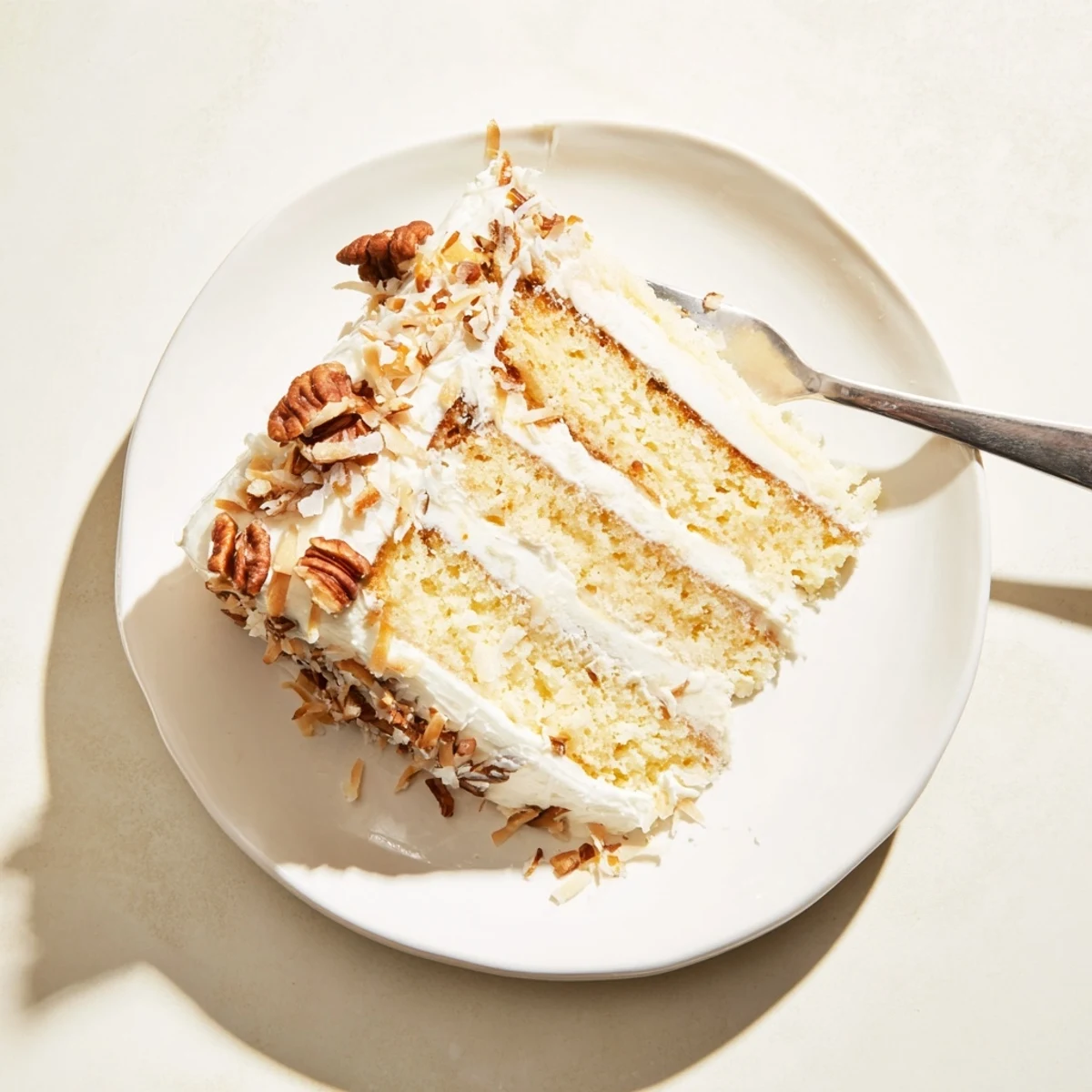 Slice of Italian Cream Cake revealing moist layers studded with shredded coconut and chopped pecans