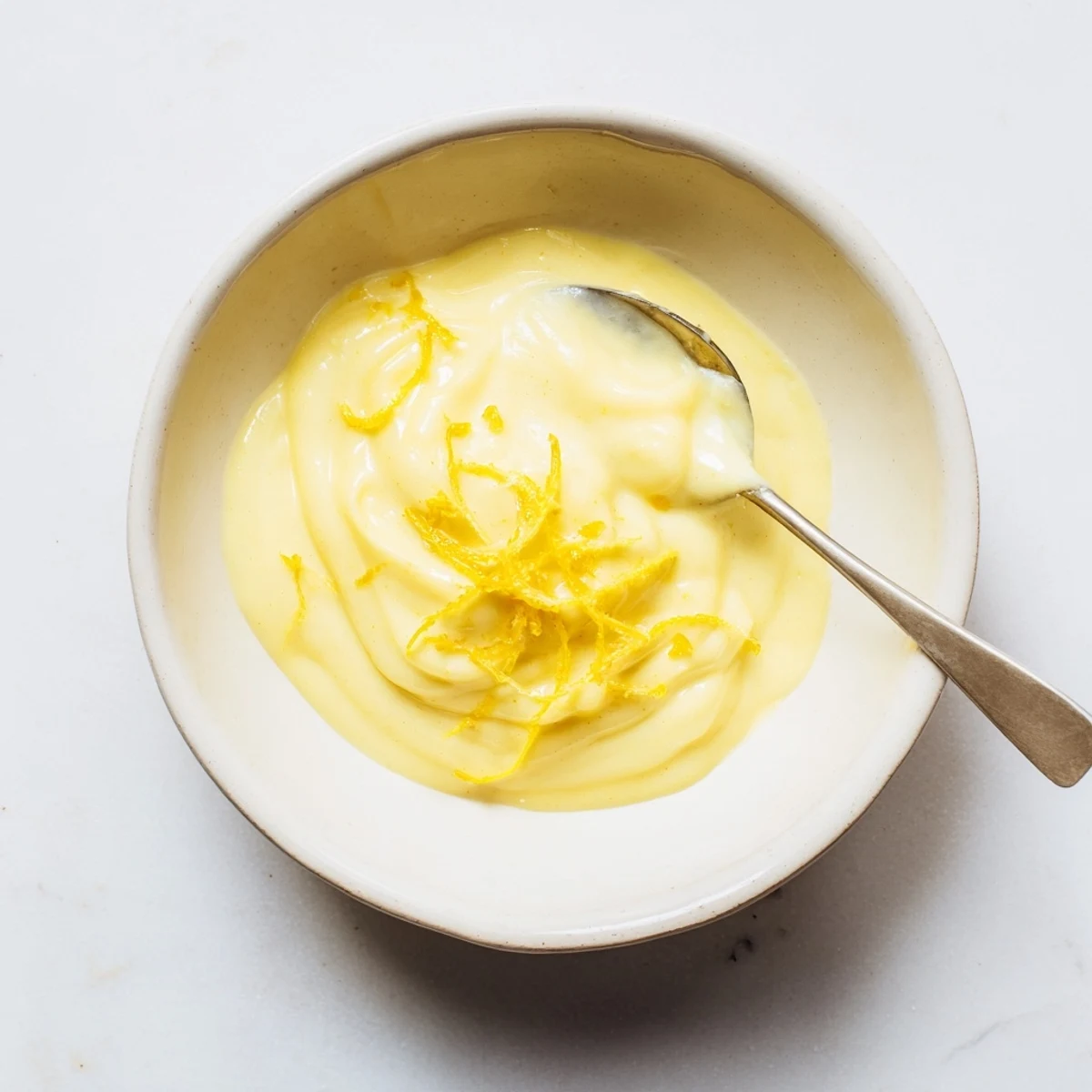 Homemade Lemon Curd spooned onto warm scone with buttery crumbs and tangy brightness