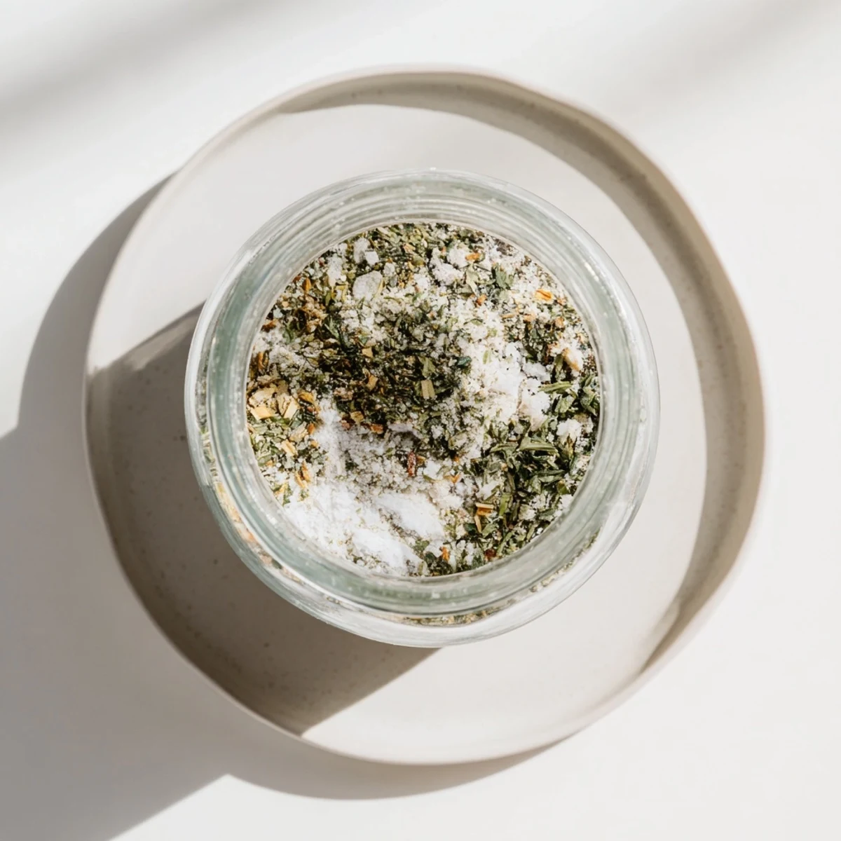 Homemade dehydrated tzatziki seasoning mix with dried dill, garlic, and parsley in glass spice jar