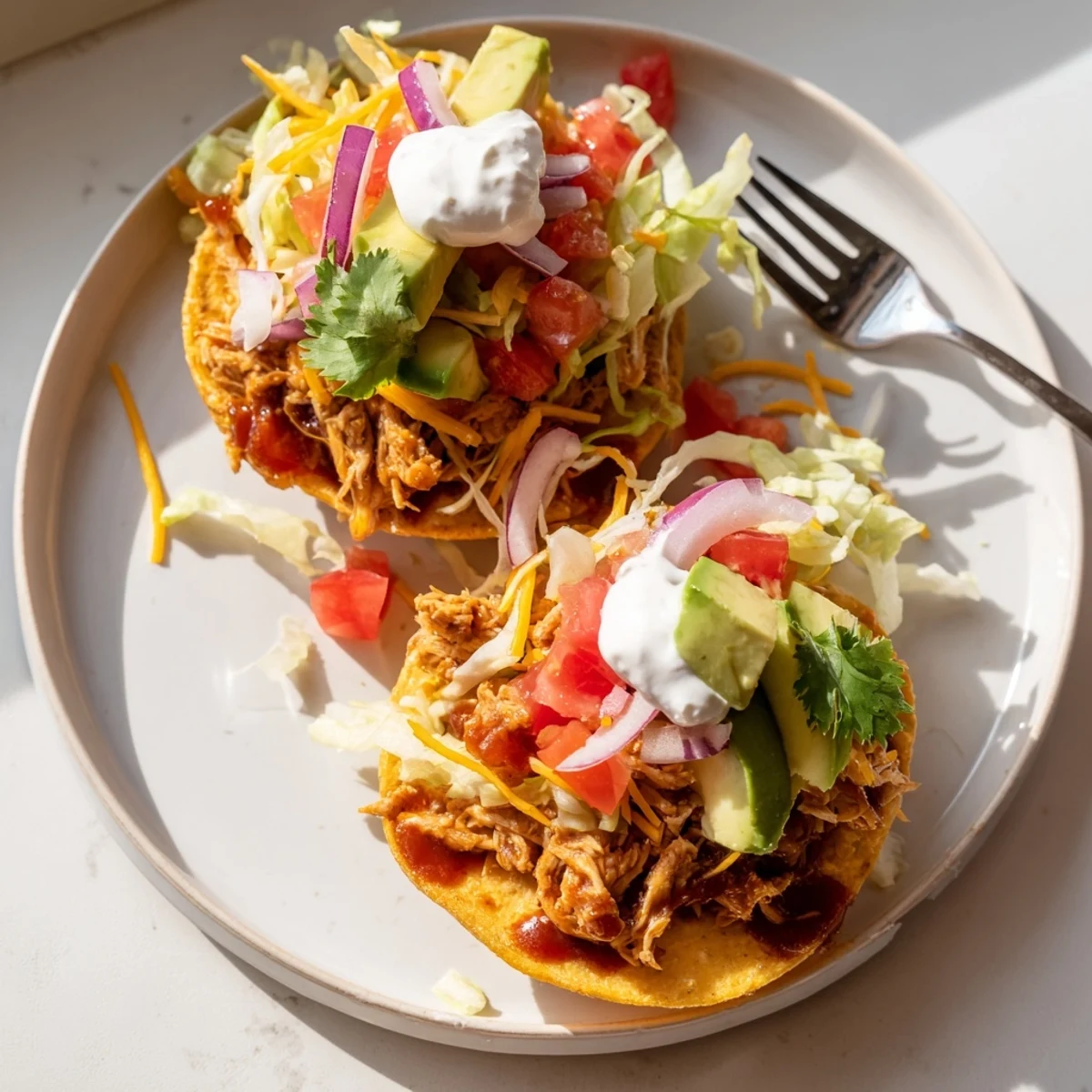 Golden tostada shells loaded with tender sweet smoky BBQ chicken, melted cheddar, and cool sour cream drizzle