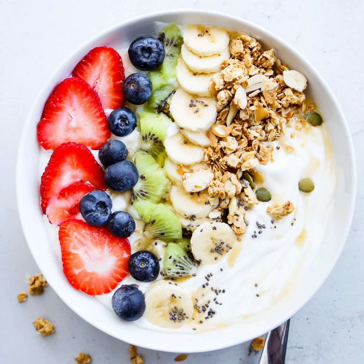 Creamy yogurt fruit bowl topped with fresh berries, banana, and crunchy granola