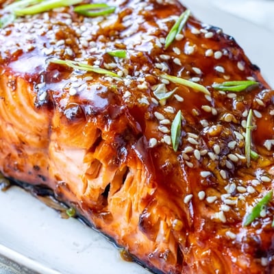 Golden baked salmon coated in glossy homemade gluten-free teriyaki sauce, scattered with sesame seeds and sliced spring onions